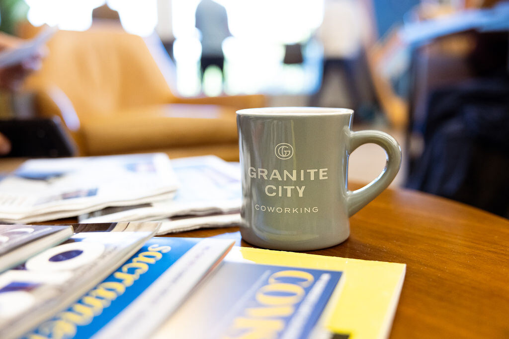Granite City Coworking branded coffee mug on a table with local Sacramento publications